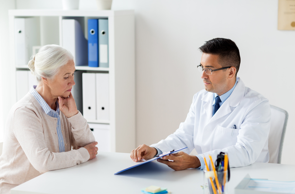 medicine, age, healthcare and people concept - senior woman and doctor with clipboard meeting at hospital