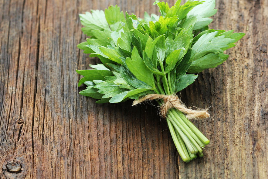 Bunch of lovage herb on wooden background .