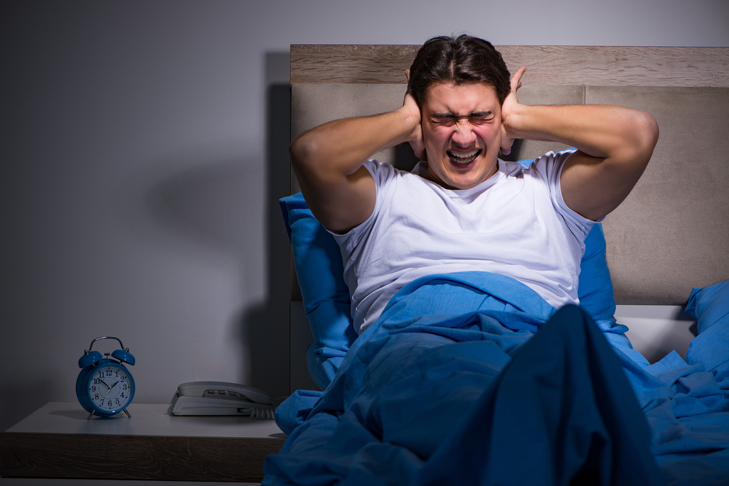 Young man struggling from noise in bed