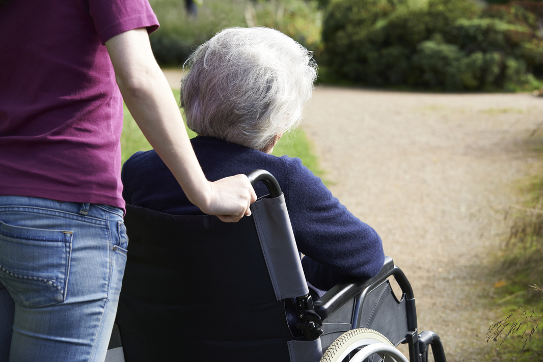 Daughter Pushing Senior Mother In Wheelchair