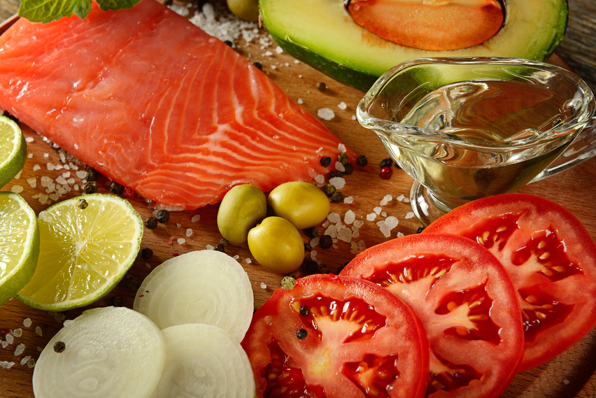 Meat red salmon fish, tomatoes, spices, green olives and olive oil on kitchen table. Top view. Selective focus.