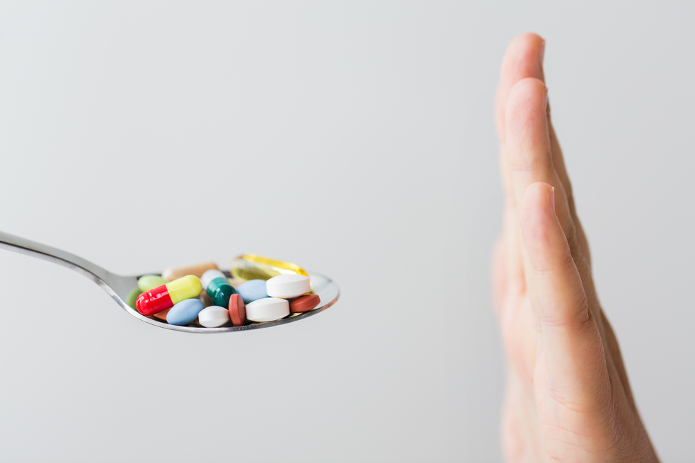 medicine, healthcare and people concept - close up of female hand holding spoon with pills